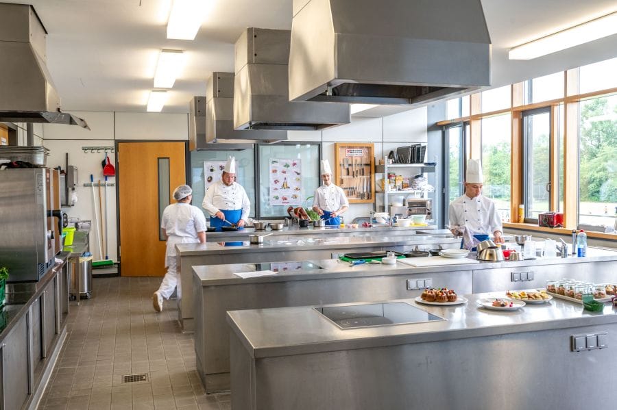 5 Köche in der Großküche beim Zubereiten von Essen