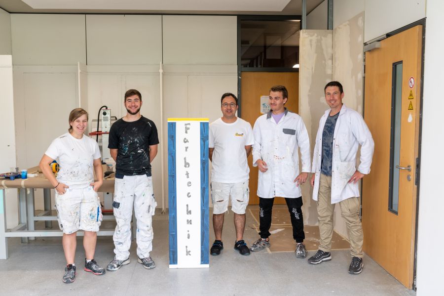 vier Maler und eine Malerin stehen im Schulungsraum