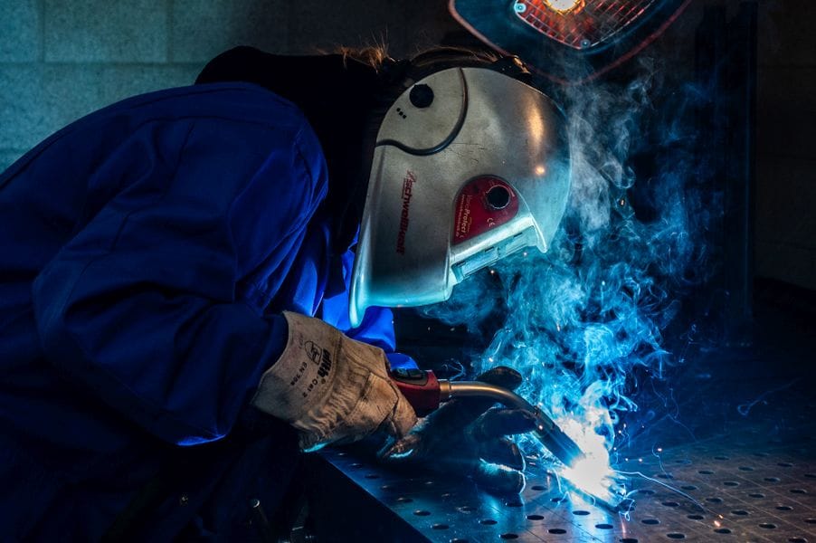 Schüler schweißt an einer Metallplatte
