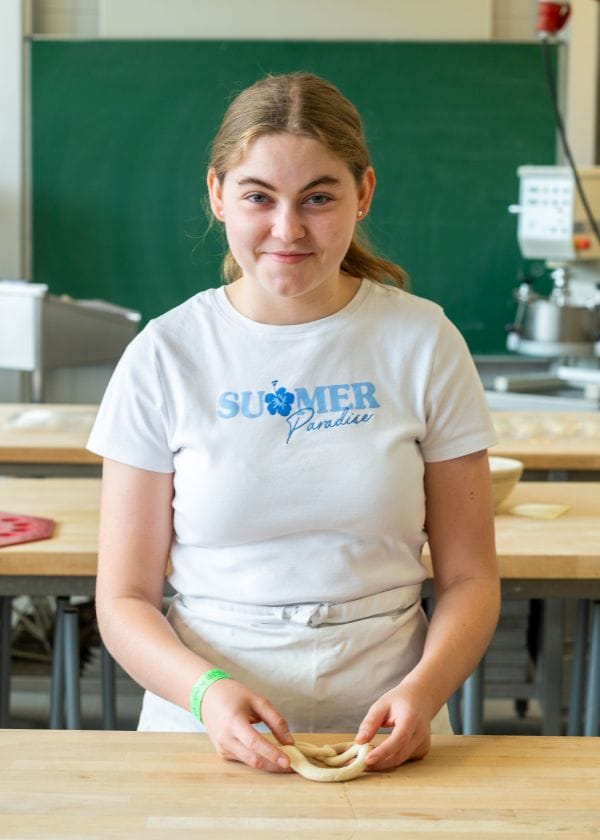 Auszubildende formt Teig in eine Breze