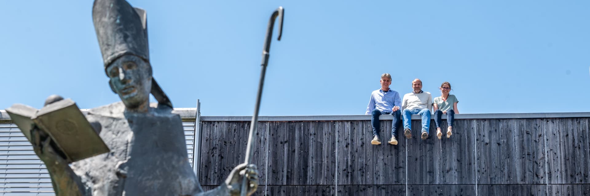 Drei Menschen sitzen auf dem Dach der Berufsschule